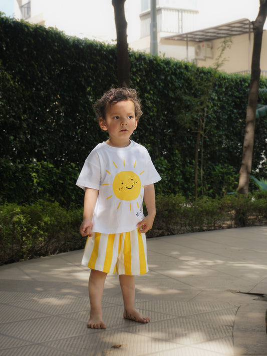 Toddler boy outdoors in Gozi's Sunny Side Up cotton T-shirt and yellow striped shorts co-ord set